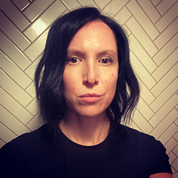 Serious looking shoulder-length brownhaired woman wearing a black top