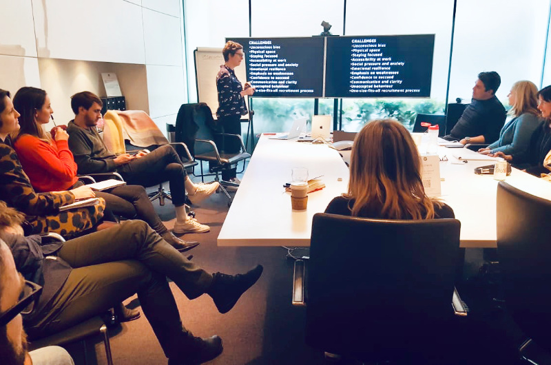 a Caucasian woman giving a presentation during a neurodiversity awareness training session