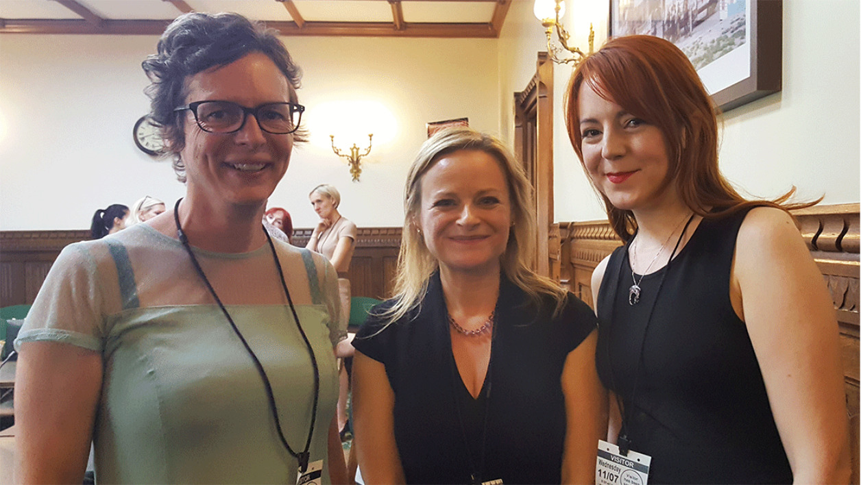 standing group of three women at an event smiling at the camera