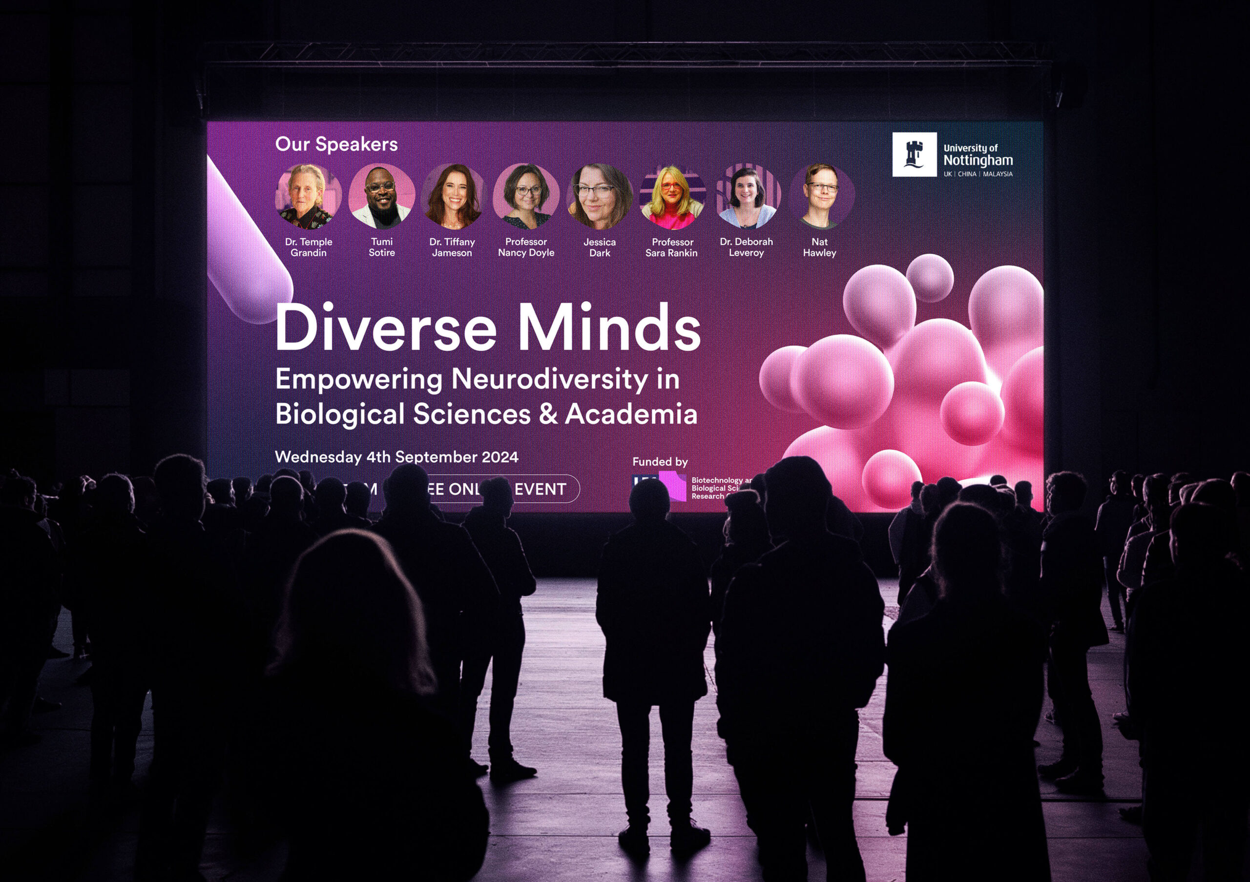 Large event screen displaying 'Diverse Minds: Empowering Neurodiversity in Biological Sciences & Academia,' with speaker photos and names, set against a purple background with 3D pink bubbles. Audience members stand in silhouette, viewing the screen.